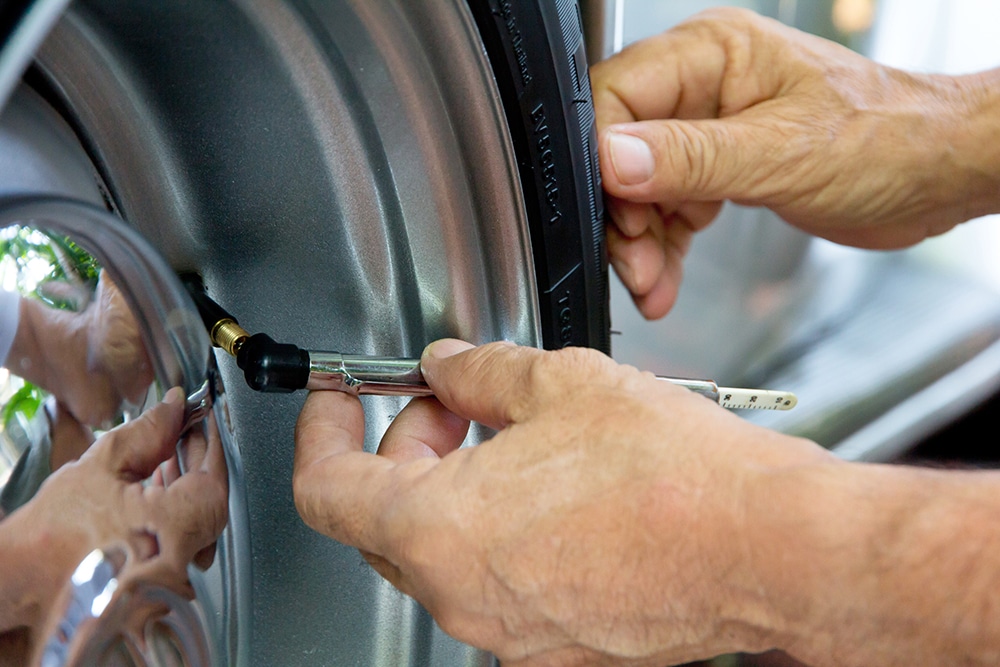 hands pressing tire gauge into tire valve